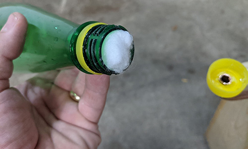 Place cotton balls in the neck of the soda bottle