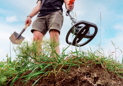 Man holding metal detector and shovel