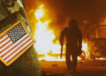 Picture with an explosion and the American flag on soldier's arm